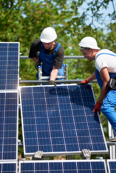 Two people installing solar panels on a metal frame