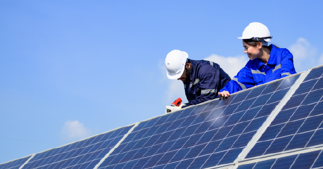 Two individuals positioning a solar panel on a roof for installation