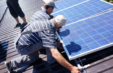 Two men installing solar panels on a roof