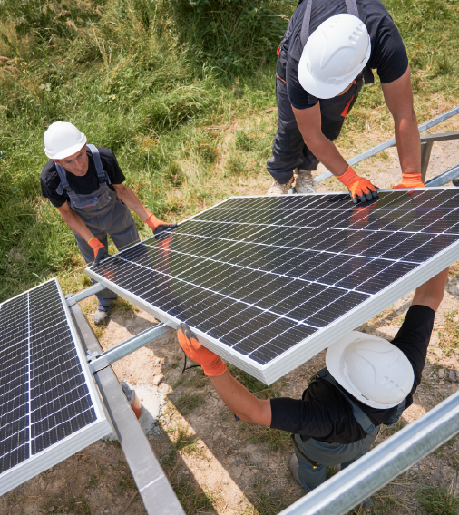 Three workers in hard hats collaborating on the installation of solar panels